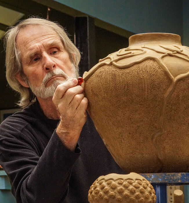 man sculpting a pot