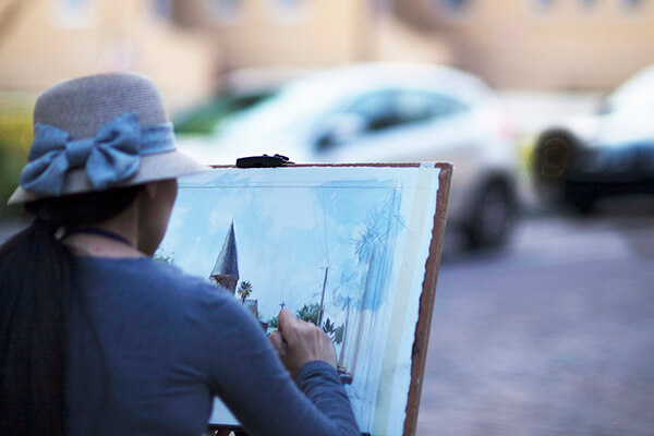 woman painting outside on an easel